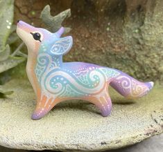 a small ceramic animal sitting on top of a rock