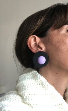 a close up of a person wearing earring's and a white sweater behind her