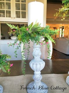 a white vase filled with flowers sitting on top of a table next to a candle