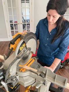 a woman using a circular saw to cut wood with a miter on the table