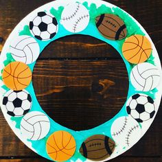 a paper plate wreath decorated with sports balls on a wooden background, ready to be used as a decoration