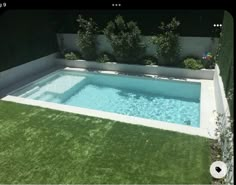 an empty swimming pool in the middle of a yard with grass and bushes around it