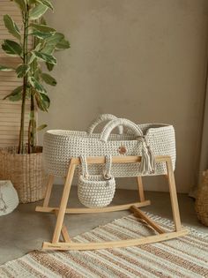 a white wicker baby's cradle next to a potted plant and rug