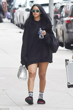 a woman walking down the street with her handbag and water bottle in her other hand