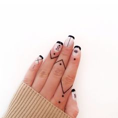 a woman's hand with black and white nail art on it, holding up her fingers