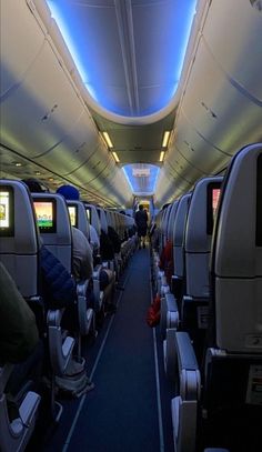 the inside of an airplane with rows of seats and blue carpeted flooring on both sides