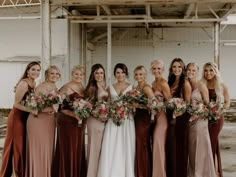 a group of women standing next to each other wearing dresses and holding bouquets in their hands