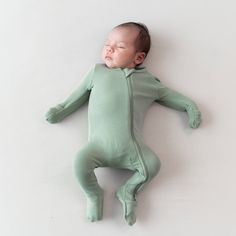 a baby is sleeping on the floor wearing a green outfit