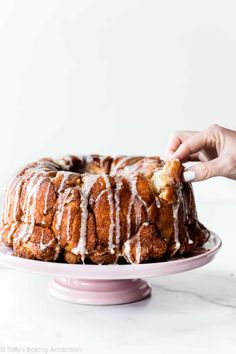 a bundt cake with icing being cut from it on a pink platter