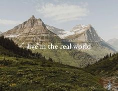 the words live in the real world are displayed on top of a green mountain range