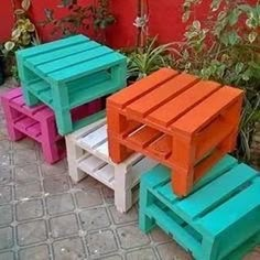 three different colored tables sitting next to each other on a brick floor in front of a red wall