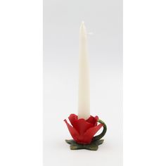 a white candle sitting on top of a red flower