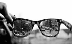 a pair of sunglasses with reflection of people walking on the street in front of them