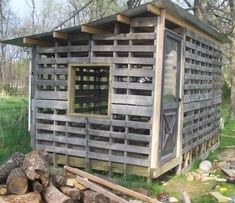 an outhouse made from wooden pallets in the woods with logs stacked around it