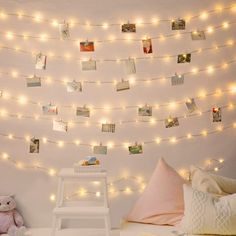 a white bed topped with lots of lights next to a wall covered in pictures and photos