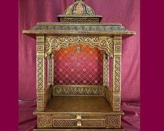 an elaborately decorated wooden shrine with red and gold paint on the wall behind it