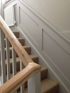 there is a wooden handrail on the stairs in this house with white walls and carpeted flooring