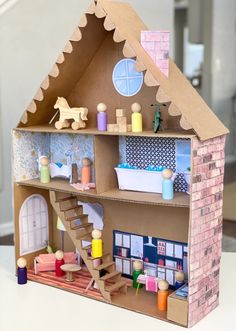 a cardboard doll house with toys on the shelves