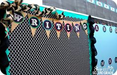 a bulletin board decorated with black and gold ribbon, brown paper streamers and some writing on it