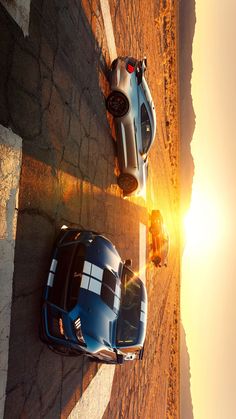 two sports cars parked next to each other on the side of a road at sunset