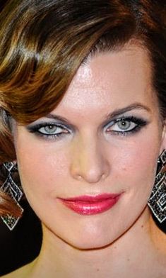 a close up of a person wearing large earrings on her head and blue eyeshadow