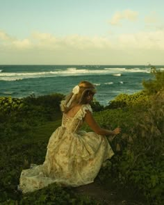 a woman in a dress is sitting by the ocean