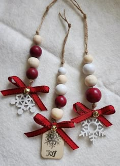 three necklaces that have snowflakes and red ribbon around them on a white surface