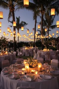 an image of a table set up for a wedding with paper lanterns in the sky