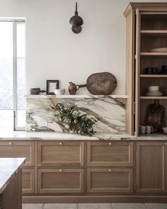 a kitchen with marble counter tops and wooden cabinets, along with pots on the wall