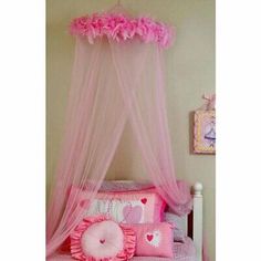 a pink canopy bed in a girls bedroom