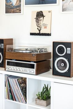 an old record player sits on top of a shelf in front of pictures and books