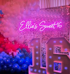 balloons and streamers decorate the backdrop for a sweet sixteen birthday party with neon lights