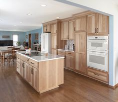 a kitchen with wooden cabinets and an island in front of the stove top ovens