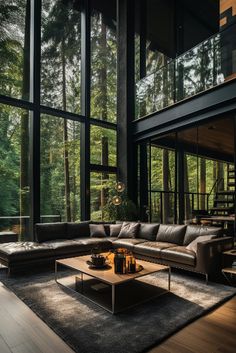 a living room filled with furniture and lots of windows next to a forest covered hillside