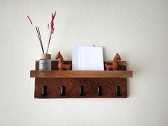 a wooden shelf with three bottles and two candles on it next to a white wall