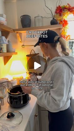 a woman is cooking in the kitchen with a pot on the stove and an orange light behind her