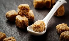 a spoon full of sugar cubes sitting on top of a black table next to other small ones