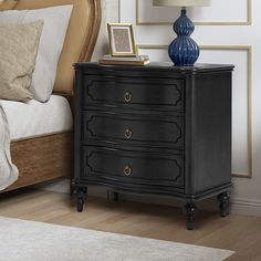 a night stand with three drawers and a blue vase on the end table next to it