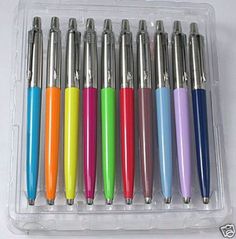 six different colored pens in a plastic container