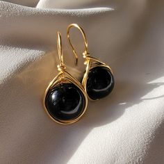 Immerse yourself in spectacular luxury with our Large Black Pearl Earrings in a drop design. These magnificent jewels fuse the timeless elegance of pearls with a touch of contemporary boldness, offering a stunning visual impact. Each majestically selected black pearl hangs gracefully in a generous drop design, providing unmatched visual appeal. The fullness of these black pearls adds a touch of drama and sophistication to your style, turning your every move into a fashion statement. The meticulously crafted setting, available in gold fill enhances the natural beauty of the pearls and adds a touch of opulence to these earrings. These jewels are not only accessories, but masterpieces that will transform any occasion into an elegant event. Whether for a special evening or to elevate your ever Black Pearl Jewelry Design, Elegant Wire Wrapped Jewelry For Parties, Elegant Round Wire Wrapped Jewelry, Party Wire Wrapped Drop Earrings, Elegant Wire Wrapped Dangle Earrings, Elegant Wire Wrapped Drop Earrings, Elegant Teardrop Earrings Gift, Wire Wrapped Teardrop Earrings For Anniversary, Elegant Handmade Crystal Earrings For Evening