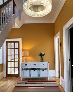 an entryway with a chandelier and rugs on the floor next to it