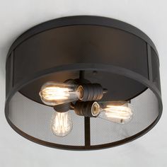 three light bulbs are attached to the ceiling in an industrial - style lighting fixture with mesh shades