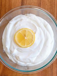 a glass bowl filled with whipped cream and a lemon slice