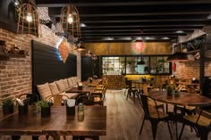 a restaurant with wooden tables and chairs, brick walls and exposed ceiling lights hanging from the ceiling