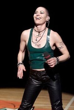 a woman standing on top of a wooden floor wearing black pants and a green tank top