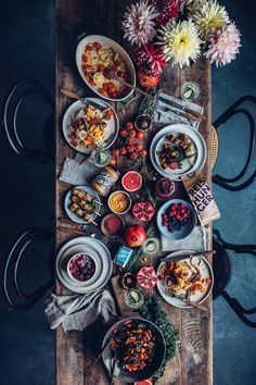 a wooden table topped with plates and bowls filled with different types of food on top of it