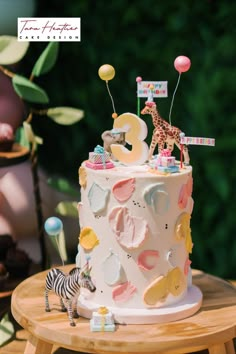 a birthday cake decorated with animals and balloons