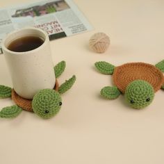 two crocheted turtle figurines next to a cup of coffee