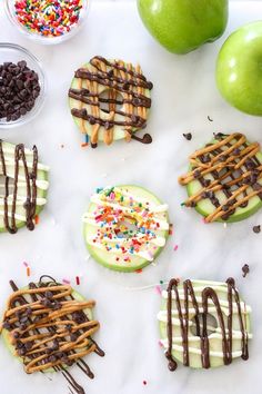 apples, chocolate and sprinkles are arranged on a white surface next to green apples