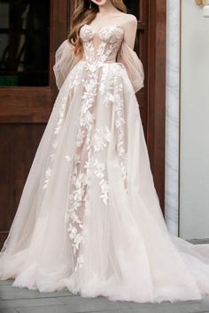 a woman standing in front of a door wearing a wedding dress with flowers on it